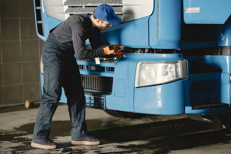 Pre ITV con desplazamiento ITV en Siero A mechanic inspects a truck's engine in a garage, showcasing skill and focus.